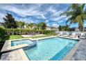 Inviting pool with hot tub, artificial turf, lounge chairs, lush landscaping, and a blue sky at 7623 Wilmington Loop, Kissimmee, FL 34747