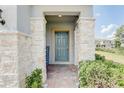 Front entrance with teal door, stone columns, and welcoming mat at 828 Scrub Oak Hammock Rd, Davenport, FL 33837