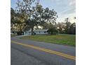 Light blue home with mature trees, manicured lawn, and asphalt driveway leading to the street at 1026 Lake Jessamine Dr, Orlando, FL 32839