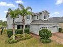 Elegant home featuring a well-manicured lawn, a brick driveway, and a two-car garage at 16737 Meadows St, Clermont, FL 34714