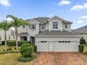 Elegant two-story home boasts a three-car garage, lush landscaping, and a brick driveway at 16737 Meadows St, Clermont, FL 34714