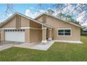 Tan house with white garage doors, walkway, and landscaping at 2749 Abney Ave, Orlando, FL 32833