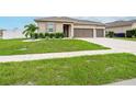 House exterior featuring a two-car garage and lush landscaping at 5681 Western Sun Dr, St Cloud, FL 34771