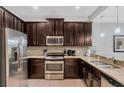 Well-equipped kitchen featuring stainless steel appliances, granite countertops, and dark wood cabinets at 8189 Roseville Rd, Davenport, FL 33896