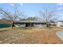 Gray brick ranch house with mature trees and a large front yard at 1201 Carol Ave, Auburndale, FL 33823