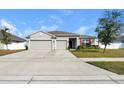 Three car garage home with a well manicured lawn at 15267 Aquarius Way, Mascotte, FL 34753