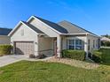 Well-manicured front lawn and shrubbery complement the home's neutral tones and well-kept two car garage at 3608 Mount Hope Loop, Leesburg, FL 34748