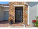A stylish front entrance with stone facade, a secure iron gate, and a vibrant potted flower arrangement at 442 Treviso Dr, Poinciana, FL 34759