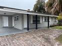 Newly renovated home with gray exterior, brick paver driveway, and covered entryway at 5640 Chet Dr, Orlando, FL 32818