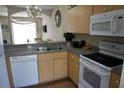 Galley kitchen with light wood cabinets, granite countertops, and modern appliances at 1128 S Beach Cir, Kissimmee, FL 34746