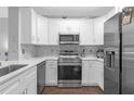 Modern white kitchen with stainless steel appliances and tile backsplash at 202 E South St # 1048, Orlando, FL 32801