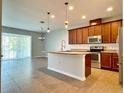 Open kitchen with island, stainless steel appliances, and wood cabinets at 2646 River Landing Dr, Sanford, FL 32771