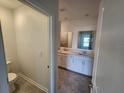 Well-lit bathroom featuring dual sinks, white cabinets, a toilet, and neutral tile flooring at 2713 Runners Cir, Clermont, FL 34714