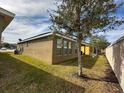 View of the back of the home and backyard with lush grass and a mature tree at 2931 Top Water Way, Kissimmee, FL 34746