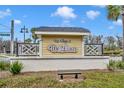 Attractive community sign for 'The Village of De Luna', set against a backdrop of lush greenery and blue skies at 3065 Sentell St, The Villages, FL 32163