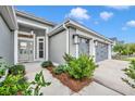 Side view of a gray home featuring a three-car garage, manicured landscaping, and a well-maintained driveway at 3065 Sentell St, The Villages, FL 32163