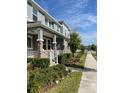 Inviting townhomes with brick accents, porches, and lush landscaping, offering a welcoming curb appeal on a sunny day at 8066 Glenlloyd Ave, Winter Garden, FL 34787