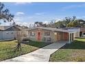 Tan mid-century modern home with orange door and a carport at 1514 Doreen Ave, Ocoee, FL 34761