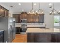 Kitchen with dark wood cabinets, stainless steel appliances, island, quartz countertops, and modern lighting at 15547 Hamlin Blossom Ave, Winter Garden, FL 34787