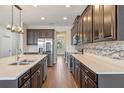 Open kitchen featuring stainless appliances, dark cabinets, quartz counters, and wood-look tile flooring at 15547 Hamlin Blossom Ave, Winter Garden, FL 34787