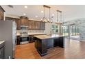 Spacious kitchen with stainless steel appliances, dark wood cabinets, island, and stylish pendant lighting at 15547 Hamlin Blossom Ave, Winter Garden, FL 34787