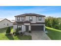 Two-story house with gray siding, brown roof, and a brick paved driveway at 175 Claffey Ct, Haines City, FL 33844
