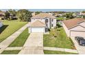 Wide aerial shot of a gray house with a large driveway and beautiful green lawn at 2120 Marisol Loop, Kissimmee, FL 34743