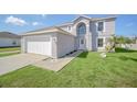 Attractive two-story home with a manicured lawn, light gray paint, and a two-car garage at 2120 Marisol Loop, Kissimmee, FL 34743