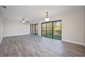 Spacious living room featuring new gray laminate flooring, ceiling fan, and a glass sliding door to the balcony at 230 Moree Loop # 4, Winter Springs, FL 32708