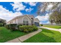 Well-manicured lawn leads to a home featuring a blue garage door and arched entryway at 2551 Bear Creek Ct, Kissimmee, FL 34747