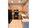 L-shaped kitchen with wood cabinets, stainless steel appliances, and tile flooring at 2586 Grand Central Pkwy # 1, Orlando, FL 32839