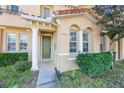 Inviting townhome entrance with verdant landscaping, an arched entrance, and a green front door at 2605 Andros Ln, Kissimmee, FL 34747
