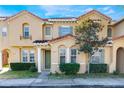 Tan two-story townhome with green door, and landscaped front yard at 2605 Andros Ln, Kissimmee, FL 34747