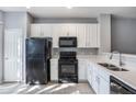 Well-lit kitchen featuring white cabinets, countertops and black appliances at 2605 Andros Ln, Kissimmee, FL 34747