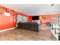 Open living room with wood-look floors, orange walls, and a comfortable gray sofa at 927 Buena Vista Ct, Orlando, FL 32818