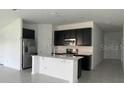 Modern kitchen with dark cabinets, stainless steel appliances, and an island at 1148 Pomelo St, Davenport, FL 33837