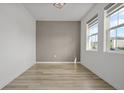 Bright bedroom with wood-look flooring, a gray accent wall, and natural light from two windows at 11842 Sunsail Ave, Orlando, FL 32832
