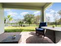 A covered back patio offers outdoor seating and serene views of the fenced backyard and a tranquil pond at 13557 Parkfield Way, Winter Garden, FL 34787
