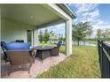 Covered patio with outdoor seating and a view of the lush backyard and a glimpse of the lake at 13557 Parkfield Way, Winter Garden, FL 34787