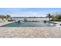 Infinity pool overlooking a scenic lake view, complete with lounge chairs and lush landscaping at 15138 Shonan Gold Dr, Winter Garden, FL 34787