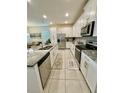 Modern kitchen featuring white cabinets, stainless steel appliances, and granite countertops with tile flooring at 1700 Tropical Palms Cir, Kissimmee, FL 34747