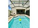 Relaxing screened-in pool with lounge chairs and a bright green ball floating in the refreshing water at 1700 Tropical Palms Cir, Kissimmee, FL 34747