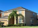 Two-story house with tan exterior, landscaping, and a two-car garage at 2553 Dharma Cir, Kissimmee, FL 34746