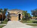 Two story house with tan exterior, landscaping, and a two-car garage at 2553 Dharma Cir, Kissimmee, FL 34746