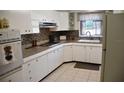 Bright kitchen features white appliances, tiled flooring, granite countertops and natural light through a window at 423 Longfellow Blvd, Lakeland, FL 33801