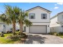 Charming two-story home with a two-car garage and a brick-paved driveway, framed by lush palm trees at 7343 Oakmoss Loop, Davenport, FL 33837
