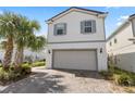 Two-story home featuring a two-car garage, brick-paved driveway and blue accents around the windows at 7343 Oakmoss Loop, Davenport, FL 33837