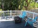 Enjoy the outdoors on this back deck with blue Adirondack chairs, fire pit, and white railings at 9263 Lake Lotta Cir, Gotha, FL 34734