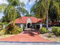 Inviting front exterior showcasing a red tile roof, paver driveway, gated entry and lush tropical landscaping at 120 W Magnolia Ave, Howey In The Hills, FL 34737