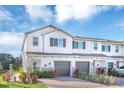 Two story townhome with gray garage doors and landscaping at 4298 Campsite Loop, Orlando, FL 32824